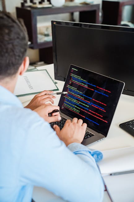 A close-up photograph of a computer screen displaying colorful lines of programming code on a dark background. The code includes various syntax highlighting with text in red, green, blue, orange, and 